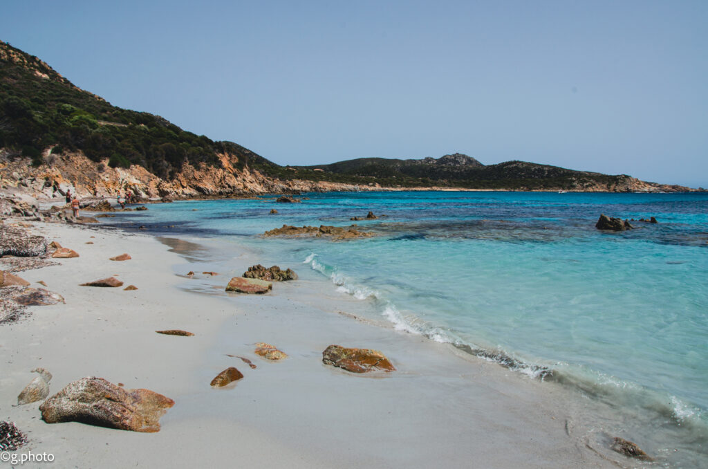 Sassi sulla riva di Cala Tuerredda con acqua limpida e luce del tardo pomeriggio. La prima meraviglia dei nostri 4 giorni in Sud Sardegna