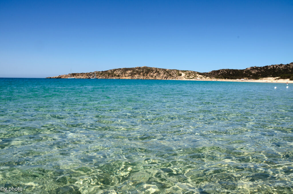 Acqua trasparente di Cala Tuerredda con il promontorio roccioso sullo sfondo